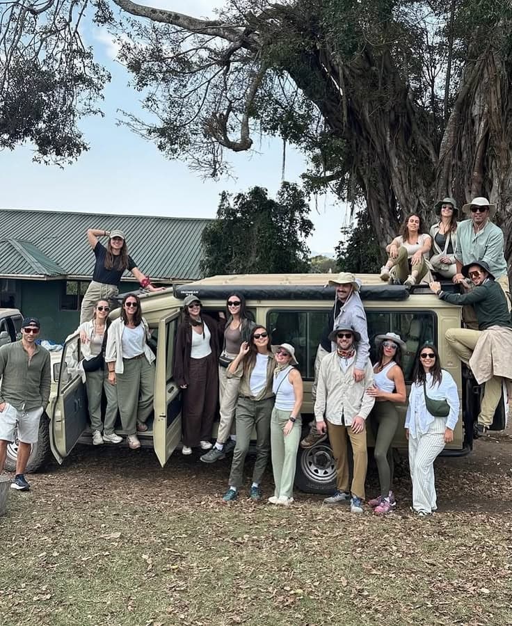 Travel group gathered around an expedition safari vehicle