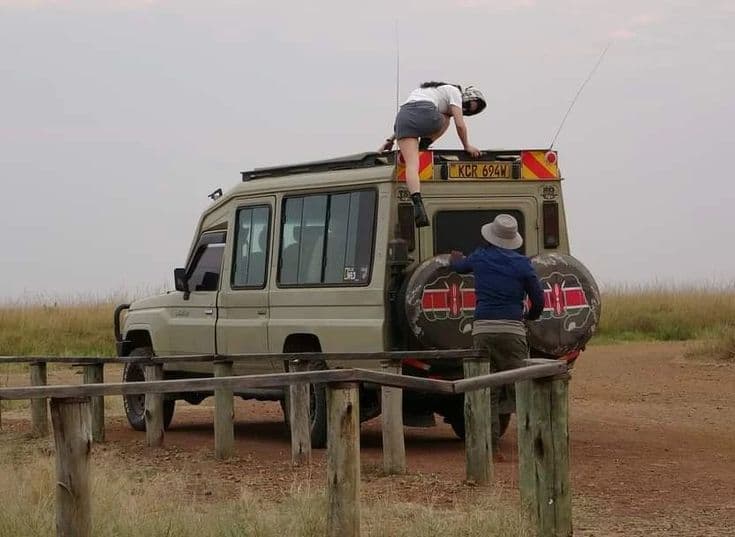 Guest climbing to the rooftop viewing deck of a safari vehicle